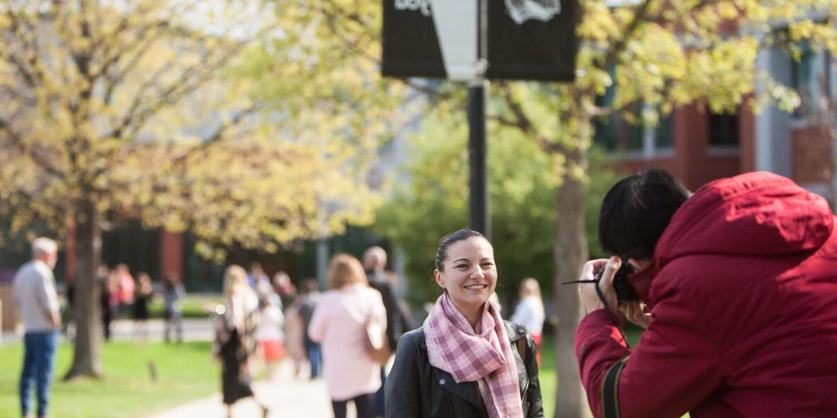 On a campus full of visitors, man stops to take a picture of a woman